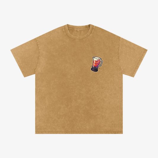 A tan short-sleeve crewneck t-shirt with a small graphic of a mug filled with red and white liquid on the left chest, displayed on a solid white background.