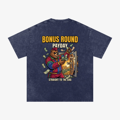 A navy blue acid-wash t-shirt shown from the back, featuring a colorful graphic of a bear character holding a safe with cash, with yellow and white text reading 'BONUS ROUND PAYDAY' and 'STRAIGHT TO THE BAG'.