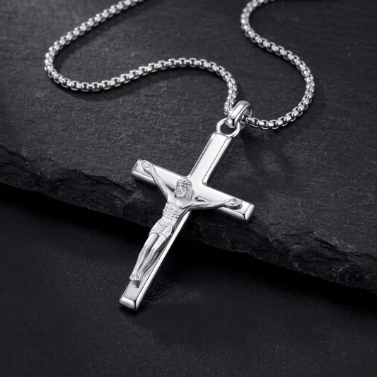 Silver crucifix pendant necklace on a box chain resting on black slate