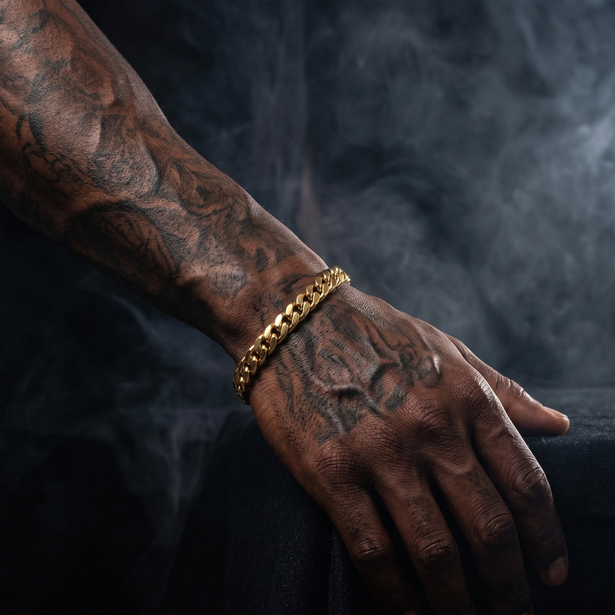8mm gold curb chain bracelet on a tattooed man's wrist