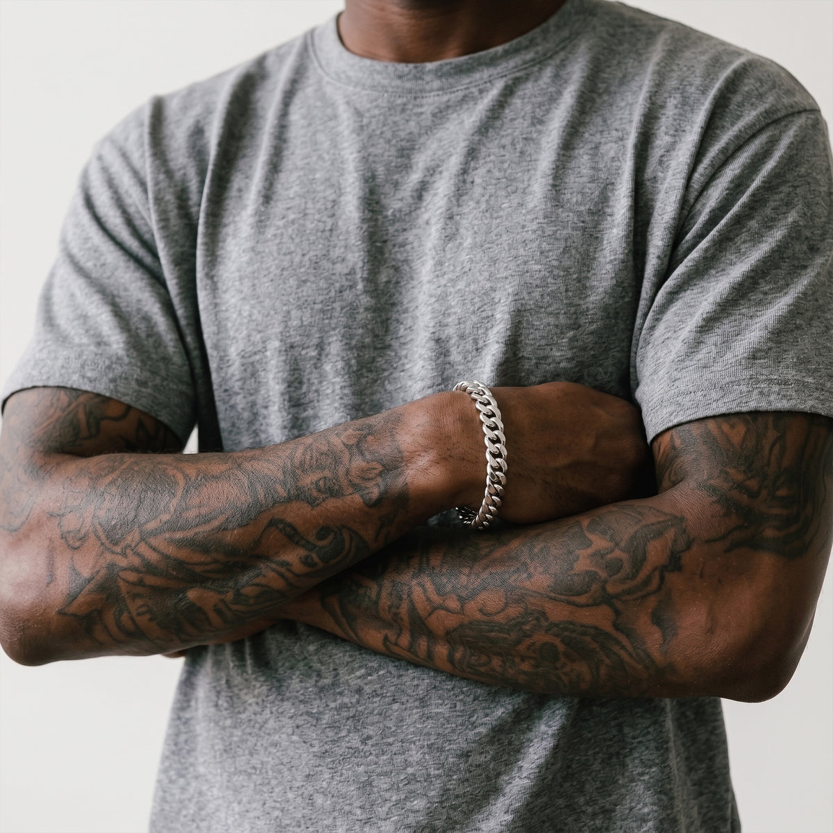 Man in a grey t-shirt with arms crossed, wearing an 8mm silver curb chain bracelet