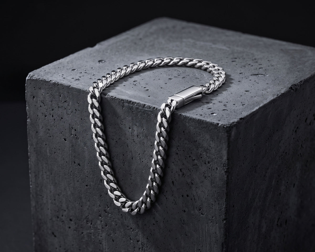 Silver 5mm curb chain bracelet draped over the edge of a dark concrete block