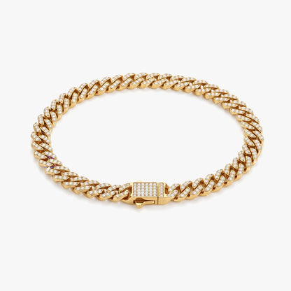 A gold Cuban link chain bracelet adorned with small clear pavé stones, featuring a rectangular clasp with a matching row of clear stones, set against a clean white background.