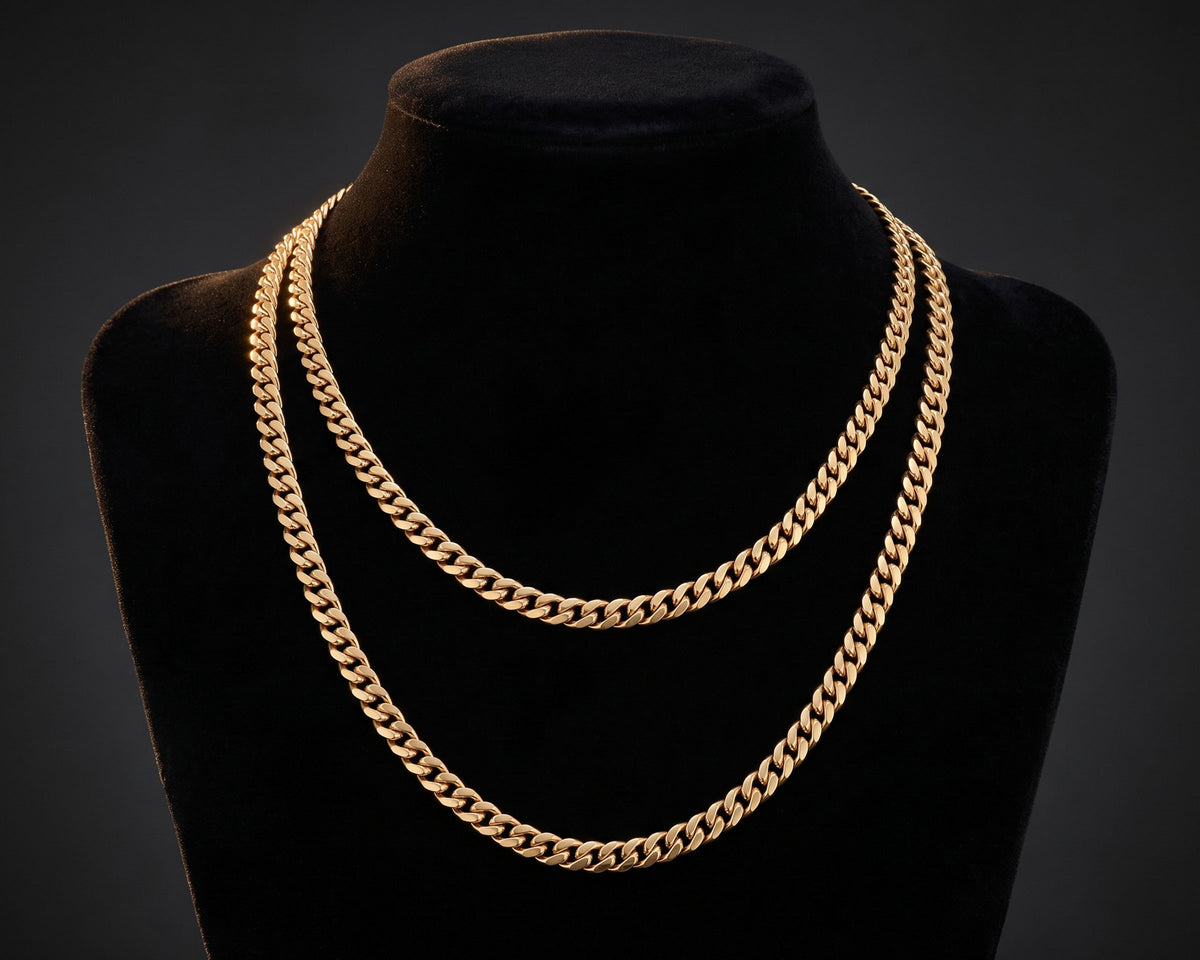 Two gold 5mm Miami Cuban chains in different lengths layered on a black velvet display bust