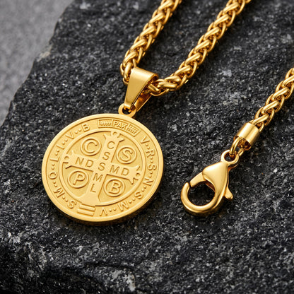 A gold-toned chain necklace with a round medallion pendant and a lobster clasp, displayed on a dark textured stone surface.