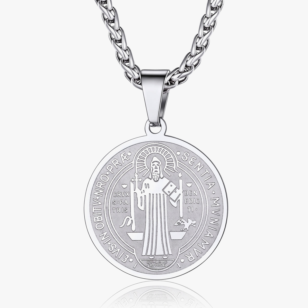 A silver-toned round pendant necklace featuring an engraved religious figure and text, suspended from a matching curb chain against a light gray background.