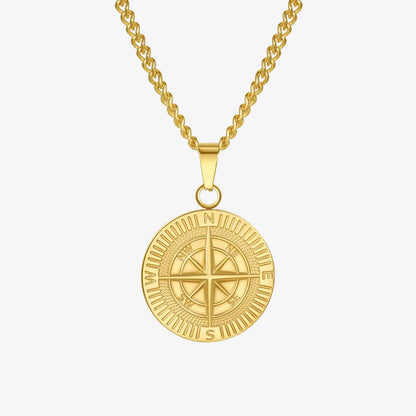 A gold-toned compass pendant necklace on a matching chain, shown against a clean white background with a subtle reflection below.