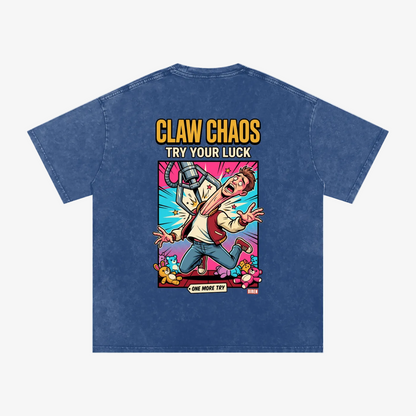 A blue acid-wash t-shirt shown from the back, featuring a large graphic print with the text 'CLAW CHAOS TRY YOUR LUCK' and a cartoon character in a dynamic action pose surrounded by colorful effects.