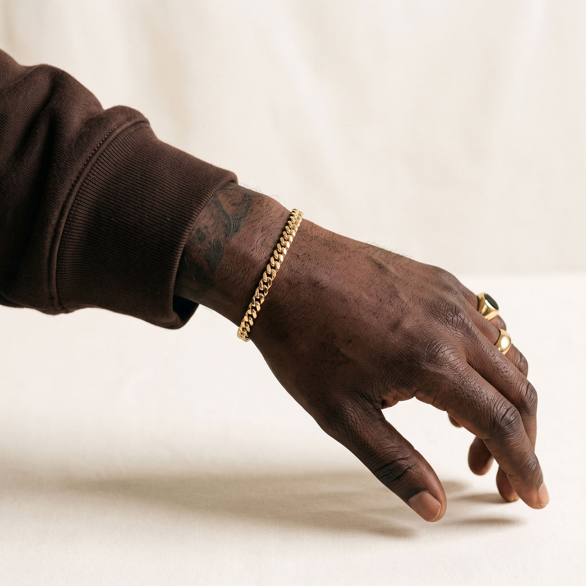 Man's hand with rings wearing a 5mm gold curb chain bracelet