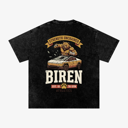 A black acid-wash graphic t-shirt featuring a muscular bear crushing a sports car with the text 'STRENGTH UNCHAINED' and 'BIREN EST. 128 GYM ATHLETICS'.