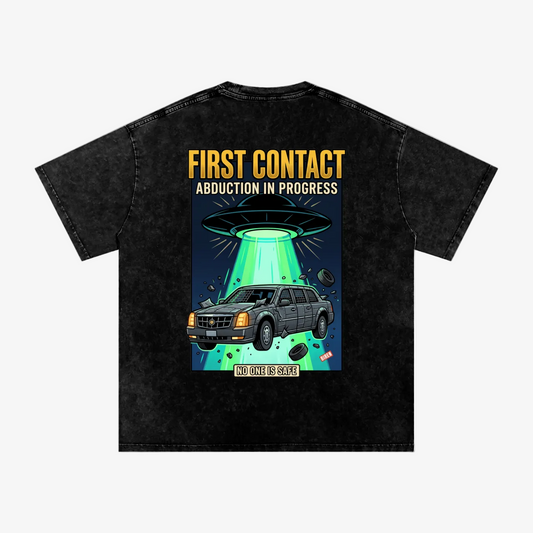 A black acid-wash graphic t-shirt shown from the back, featuring a cartoon illustration of a gray SUV being abducted by a UFO with a green beam of light, and bold yellow and white text reading 'FIRST CONTACT ABDUCTION IN PROGRESS' and 'NOT ALL IS GAIN'.